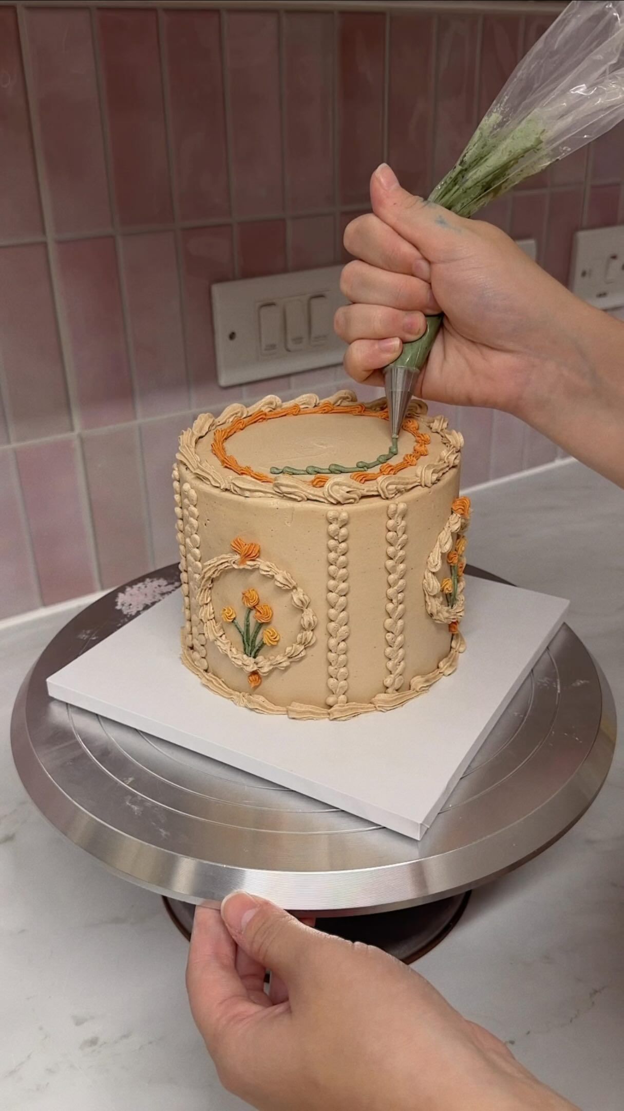 Hand-piping detail onto a caramel-toned cake